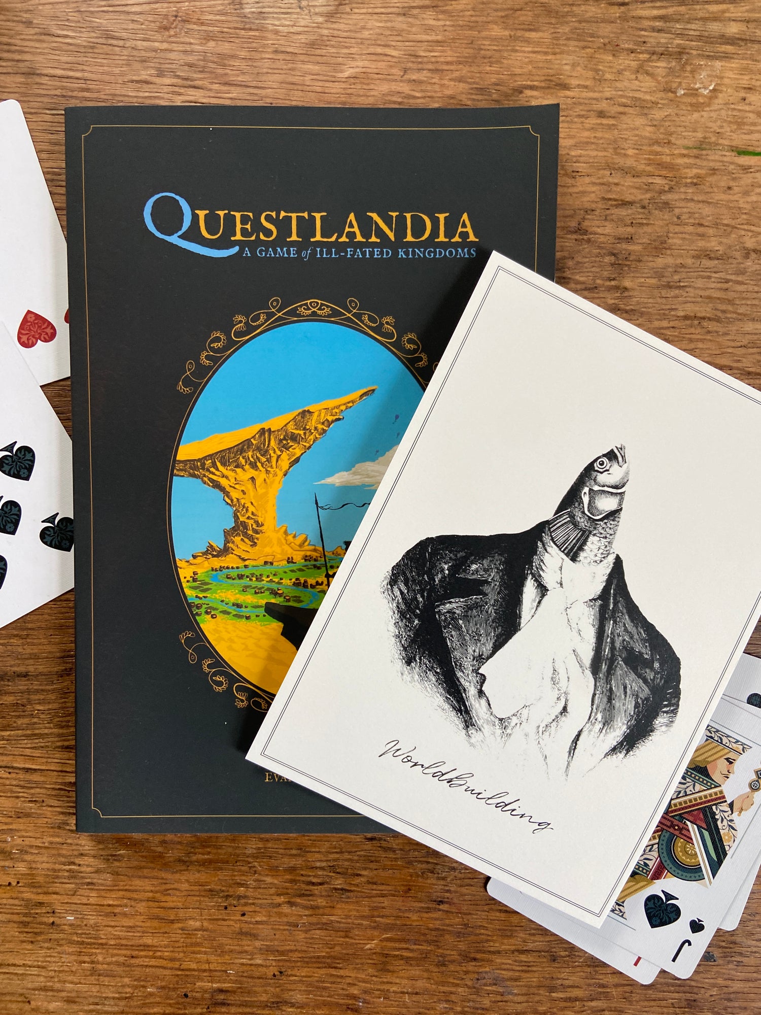 Questlandia ttrpg with playing cards and worldbuilding fish print